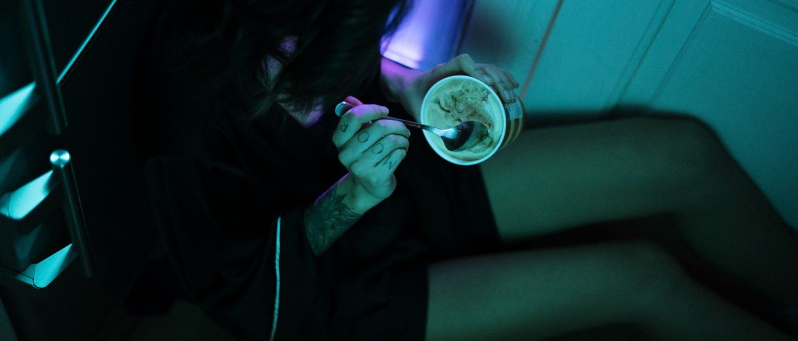 Mulher comendo sozinha na cozinha à noite